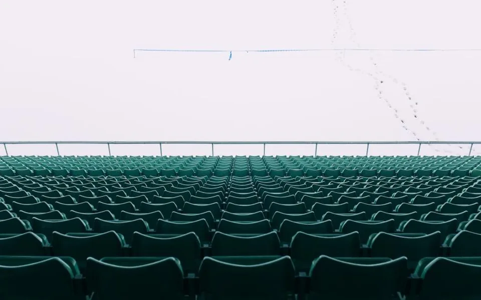 Leere Stadionsitze unter einem weißen, verschneiten Himmel