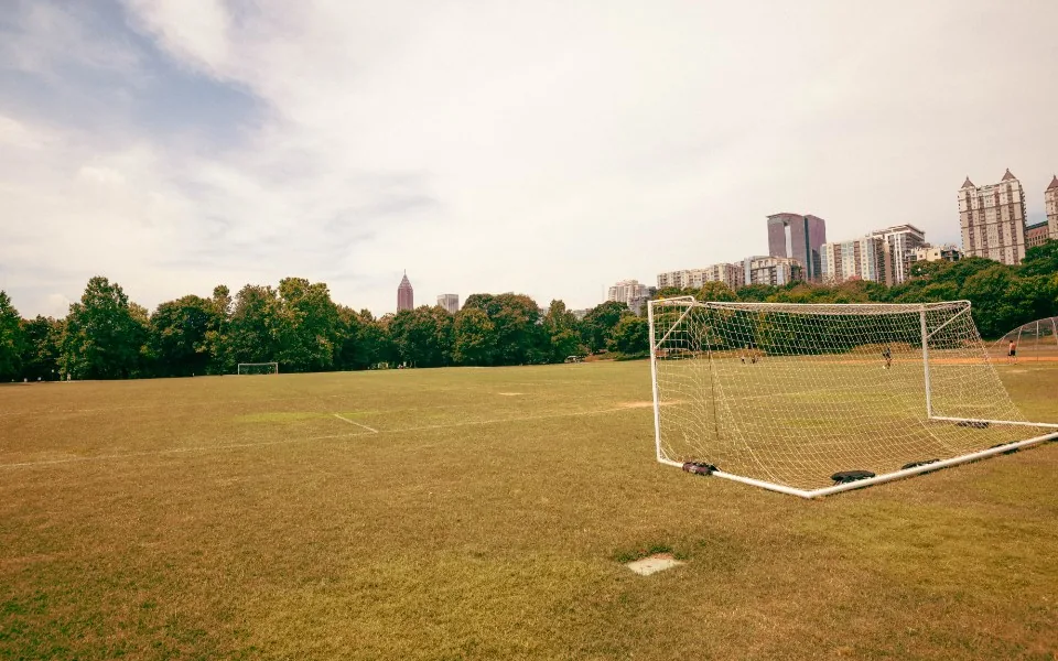 Leeres Fußballfeld mit Tor und Stadtsilhouette im Hintergrund
